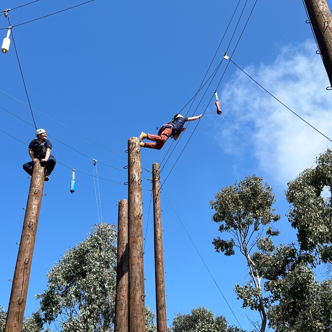 Two students leaping in a challenge course