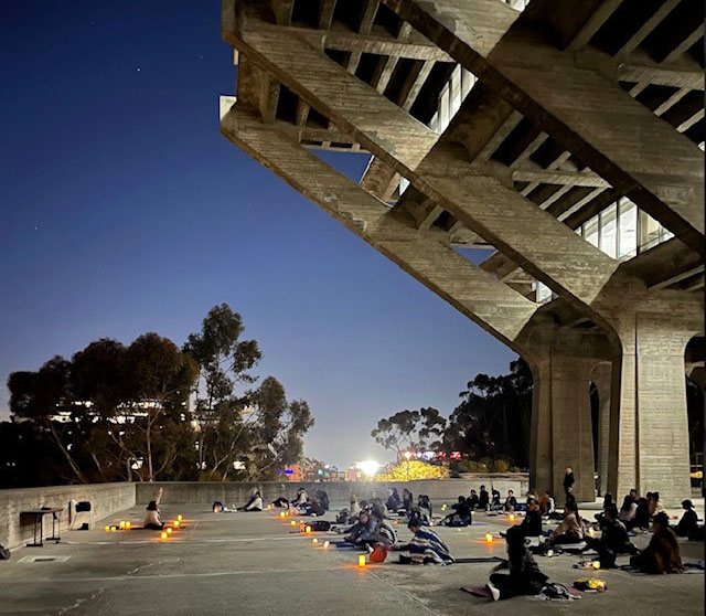 Nighttime group yoga session at the base of Geisel Library